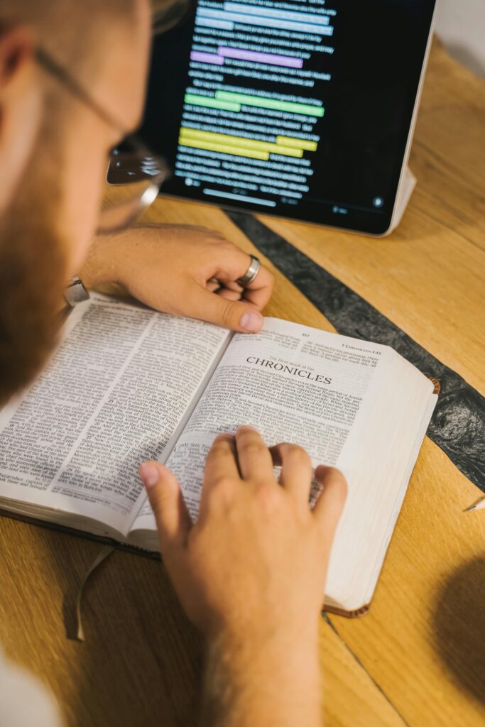 An open Bible with Chronicles being studied, accompanied by a digital tablet for reference.